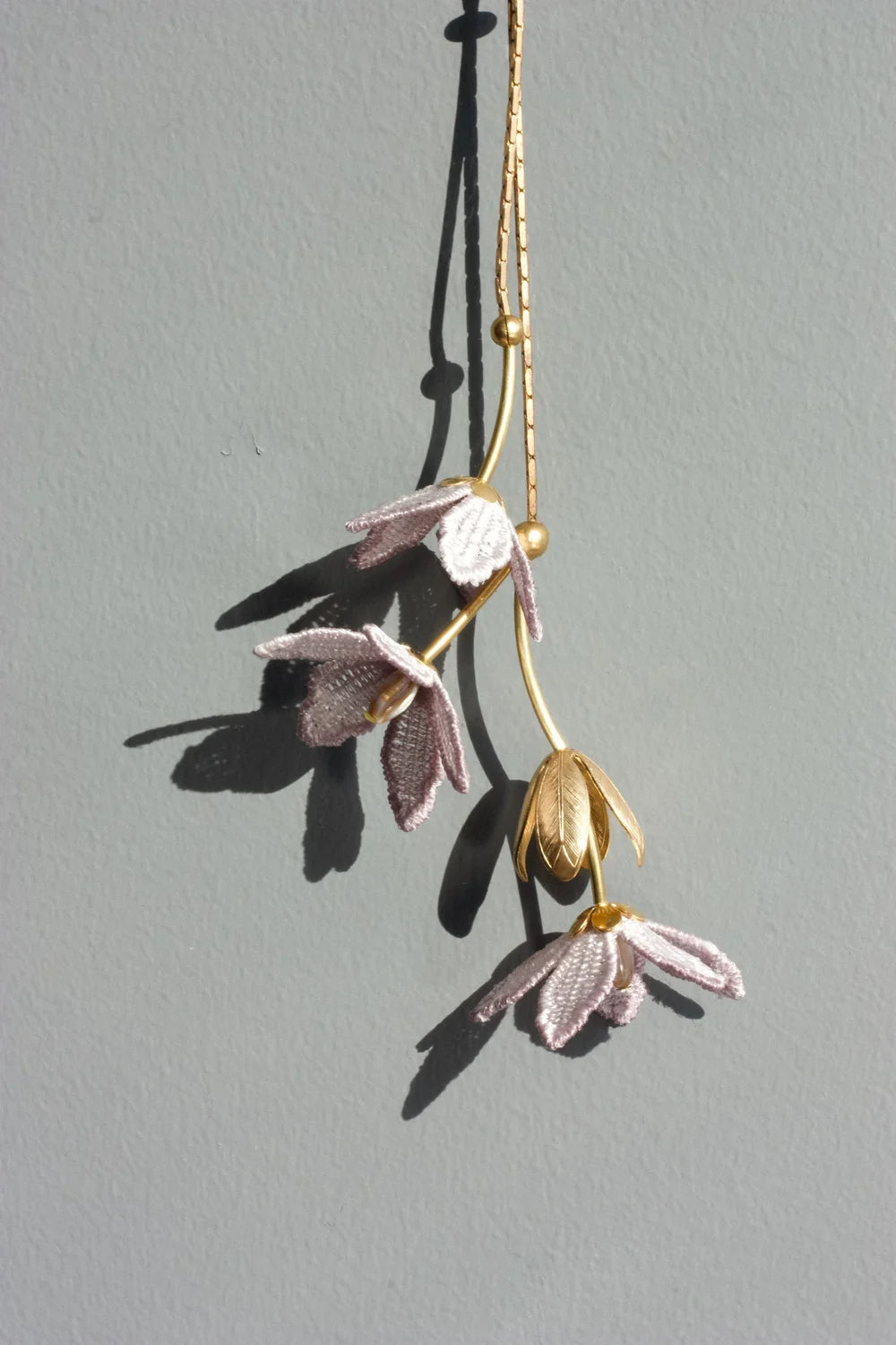 Ilk Jewelry Tahitian Gardenia flower necklace featuring a delicate chain and a blooming floral pendant in vintage lace .