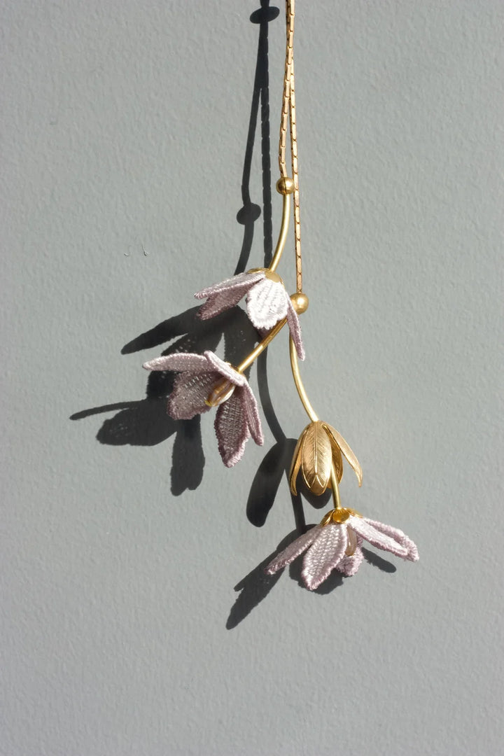 Ilk Jewelry Tahitian Gardenia flower necklace featuring a delicate chain and a blooming floral pendant in vintage lace .