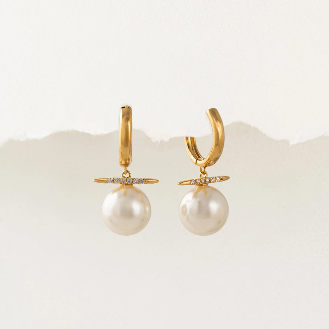 Gold hoop earrings with pearl drops on a white background