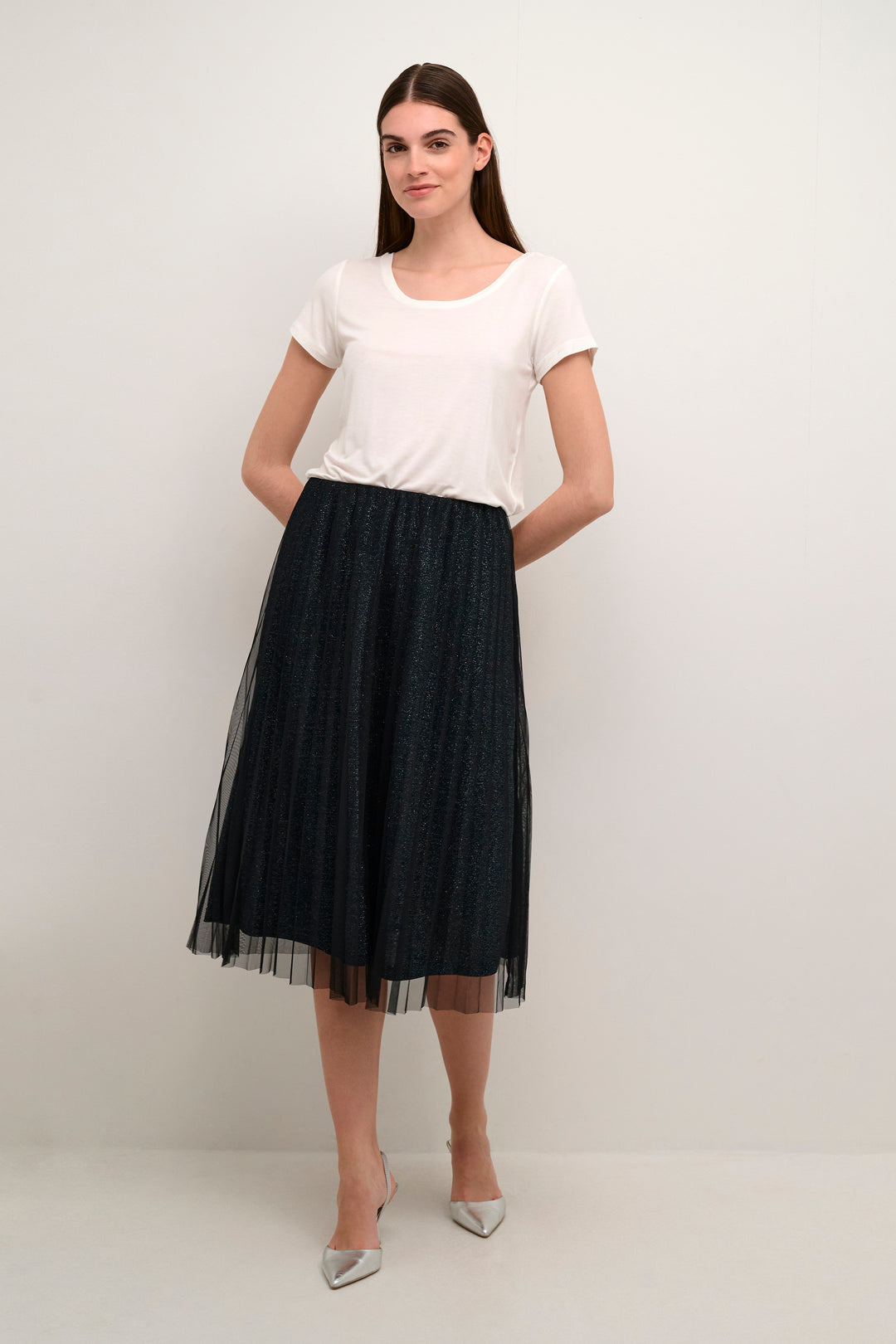 Woman wearing a white t-shirt and black tulle skirt on a plain background