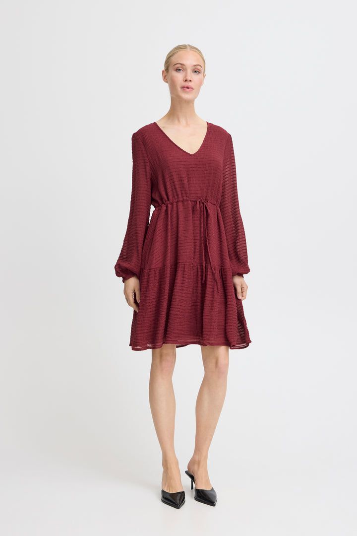 Woman wearing a burgundy dress on a white background