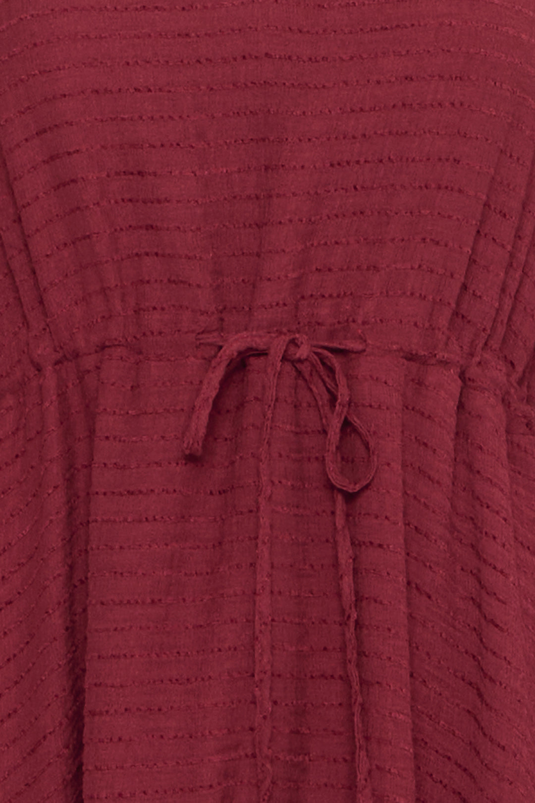 Close-up of a textured burgundy dress with a drawstring waist.