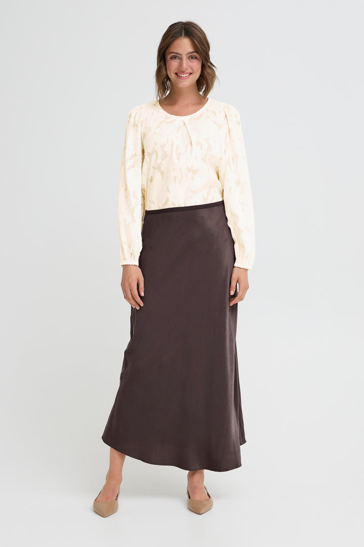 Woman wearing a cream blouse and brown skirt on a white background