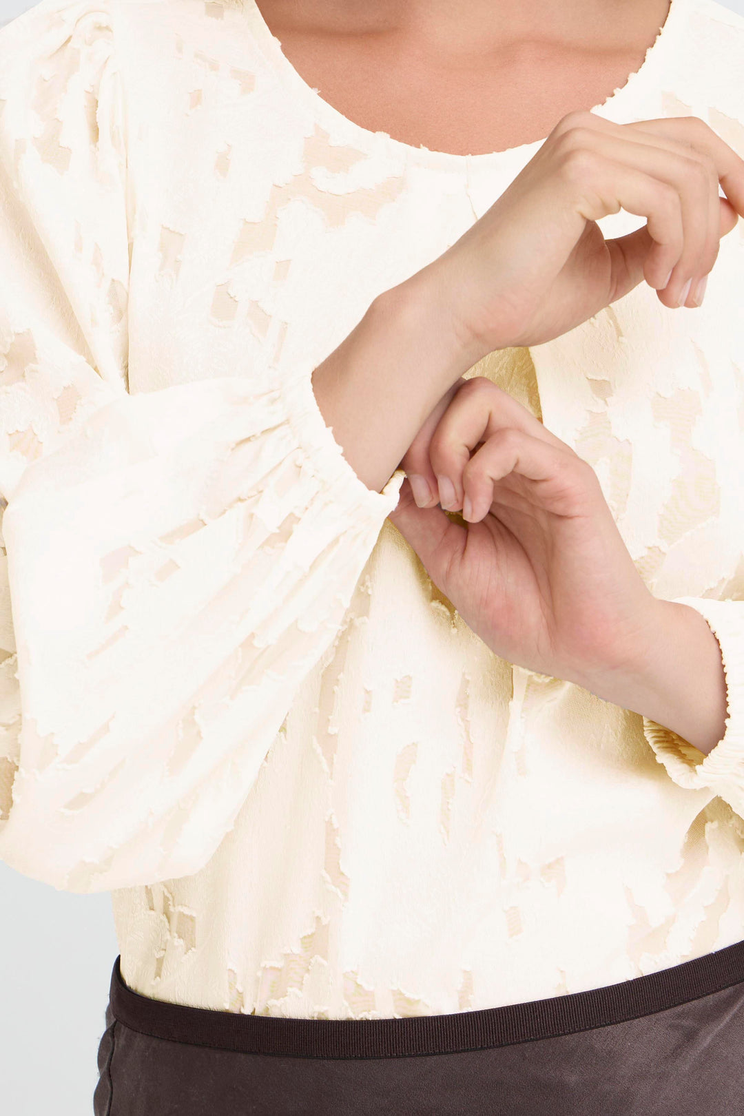 Person wearing a white lace top with a blurred background