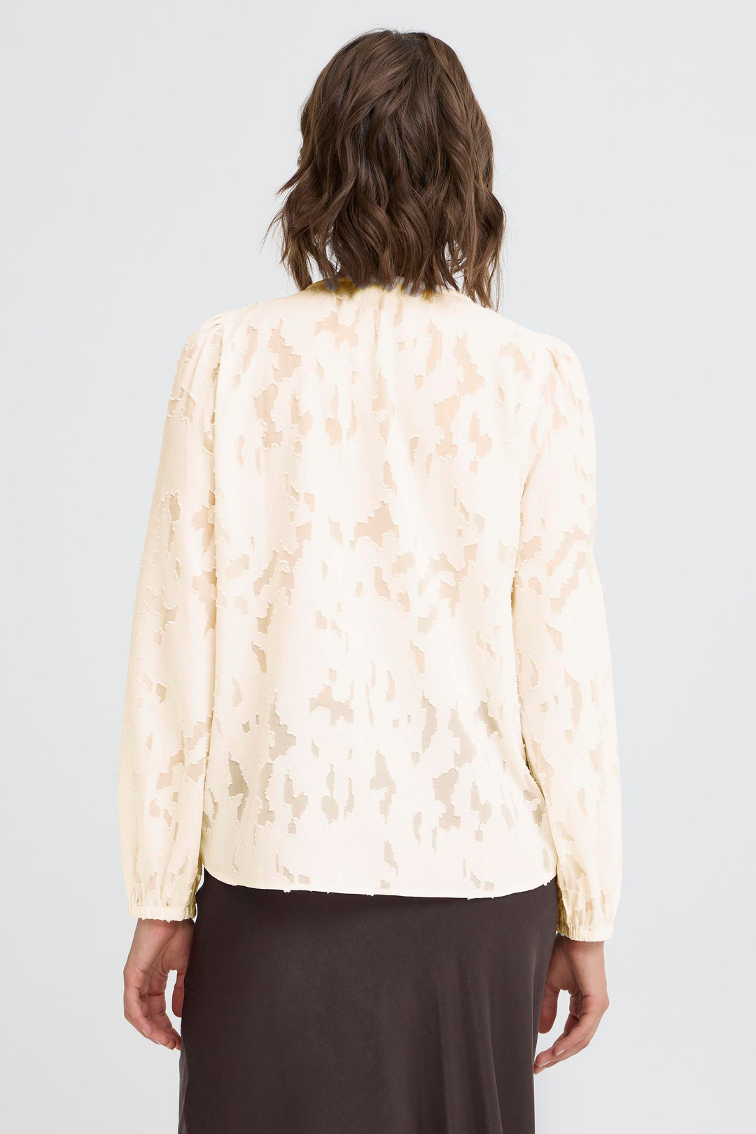 Person wearing a light-colored floral blouse against a plain background