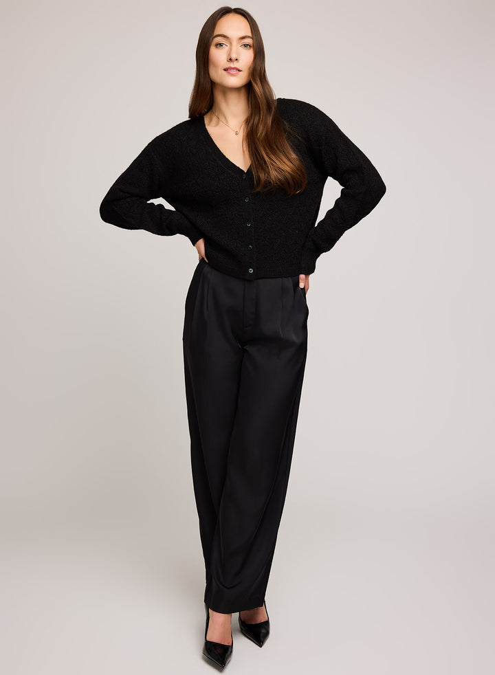 Woman wearing a black cardigan and black pants on a plain background