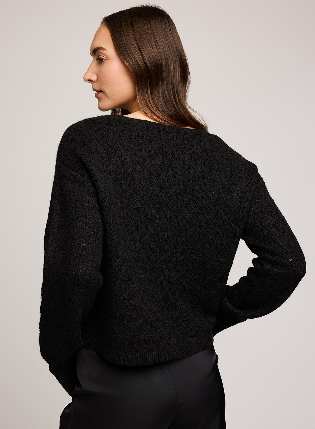 Woman wearing a black sweater against a plain background