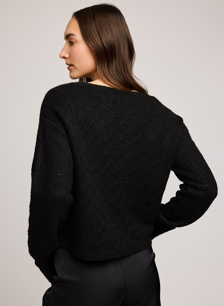 Woman wearing a black sweater against a plain background