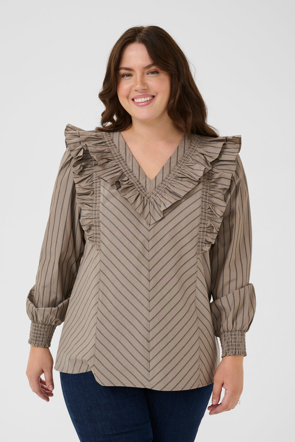 Woman wearing a brown and beige striped blouse with ruffled details on a white background
