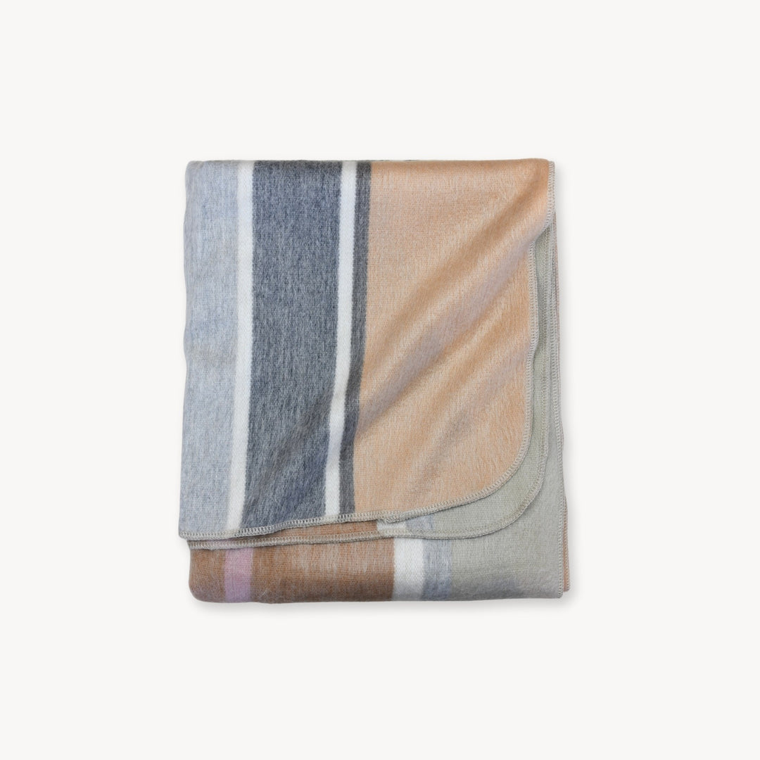 Folded alpaca wool blanket with beige and grey striped pattern on a white background