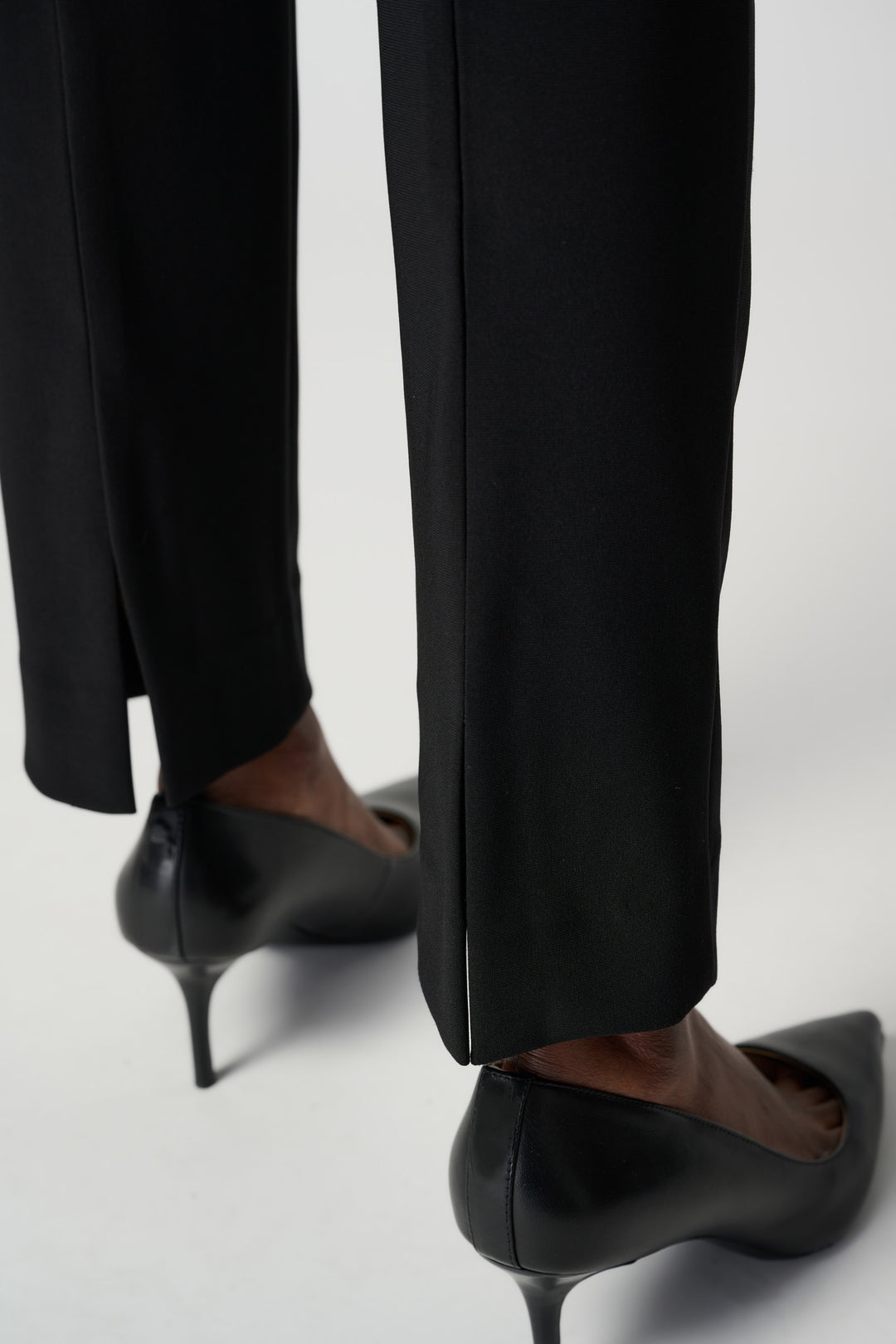 Black high-heeled shoes and pants on a white background