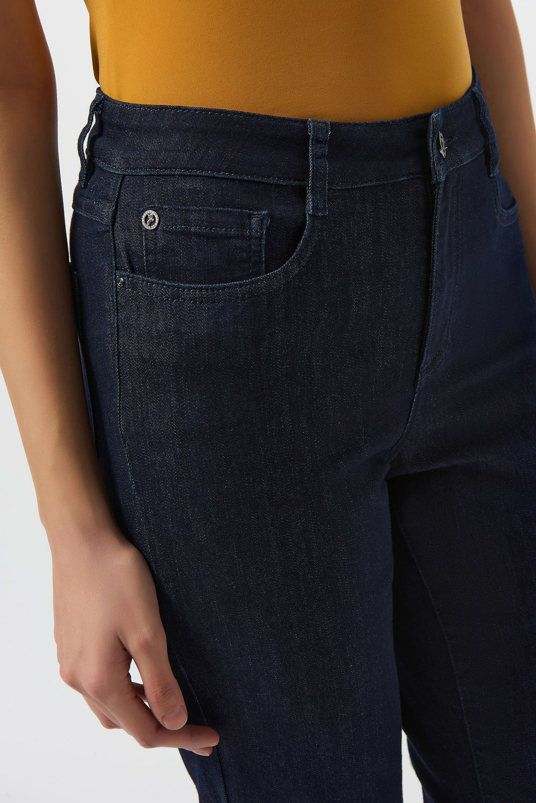 Dark blue jeans worn by a person on a white background