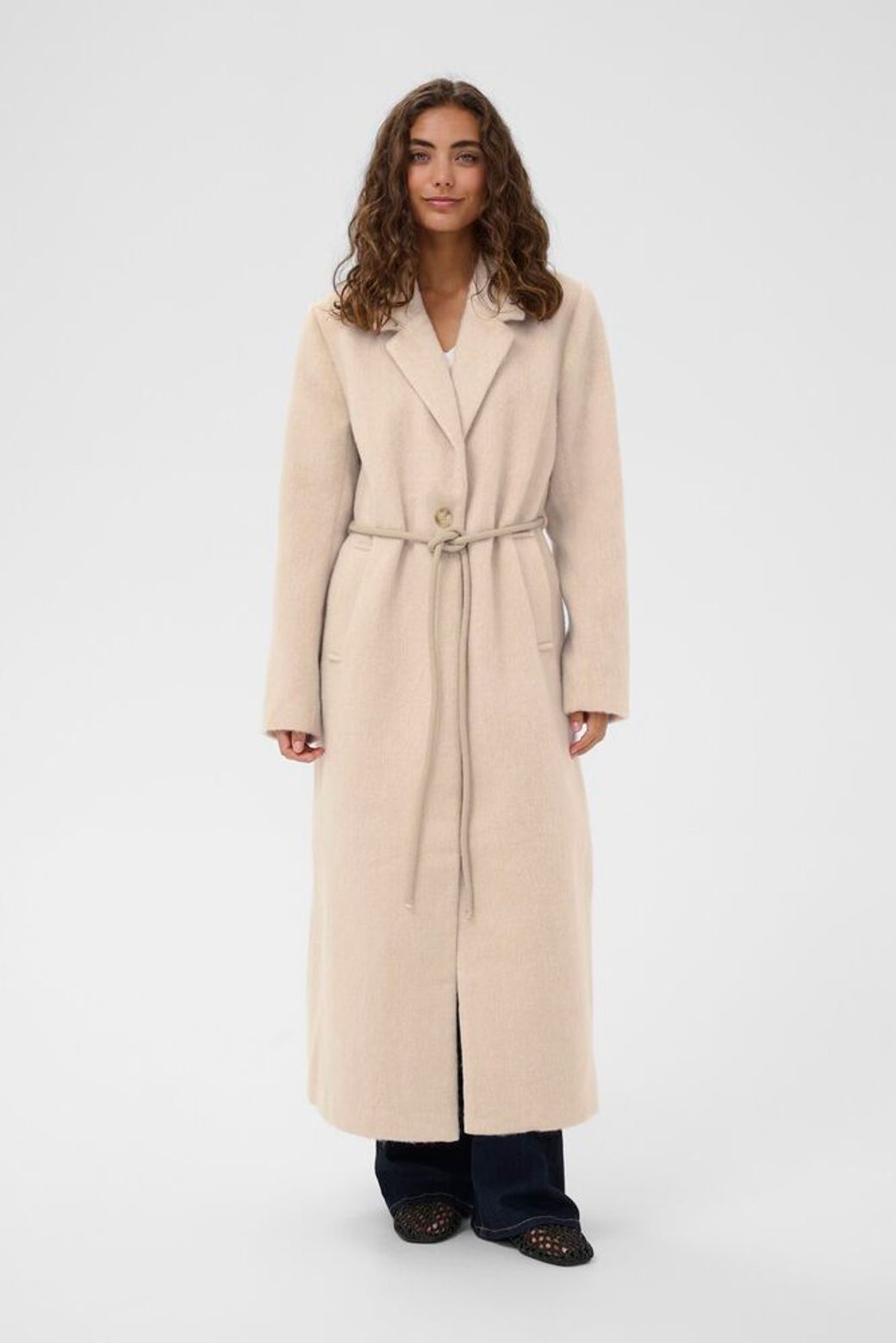 Woman wearing a long beige coat on a white background