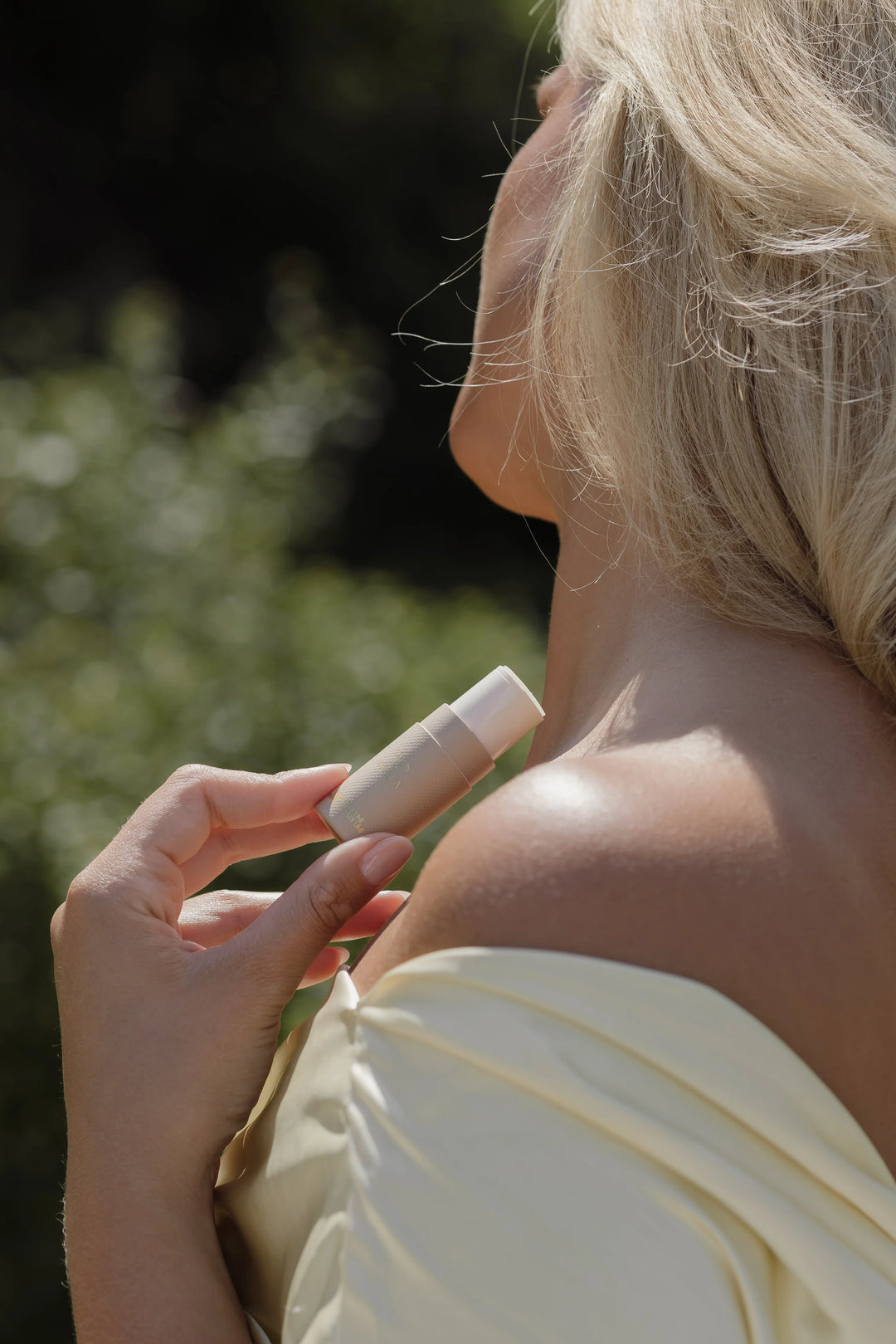 Woman applying vanilla_Solid_pefume_stick to her shoulder outdoors
