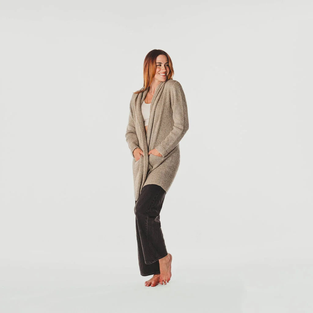 Woman wearing a long beige cardigan on a light gray background