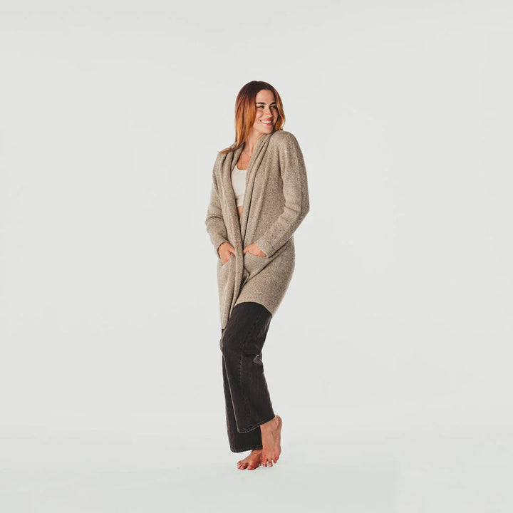 Woman wearing a long beige cardigan on a light gray background