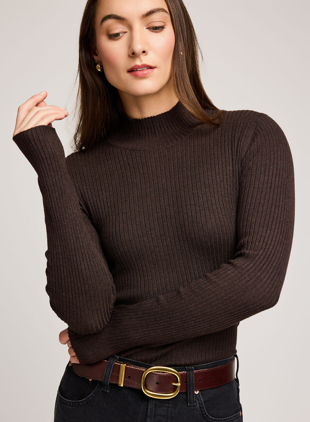 Woman wearing a brown ribbed sweater with a plain background