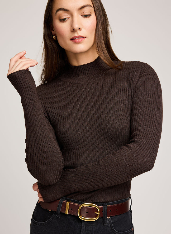 Woman wearing a brown ribbed sweater with a plain background