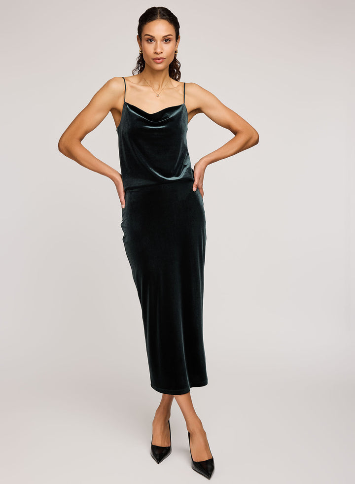 Woman wearing a dark green velvet dress on a plain background