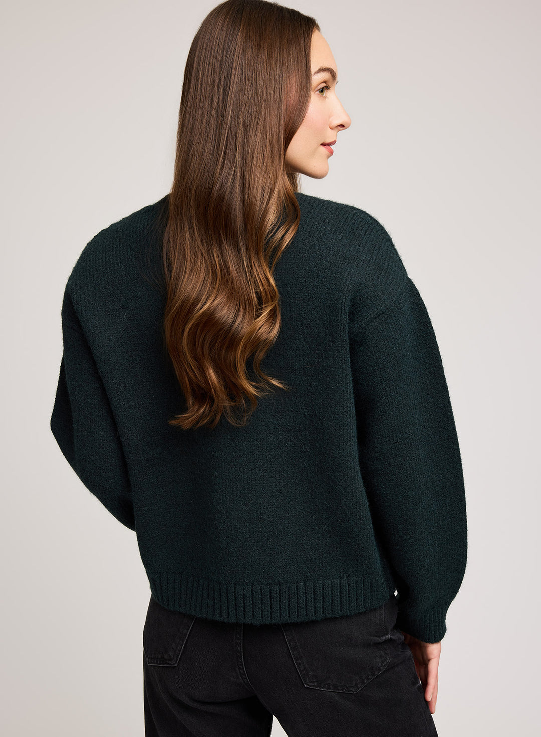 Person wearing a dark green sweater on a light gray background