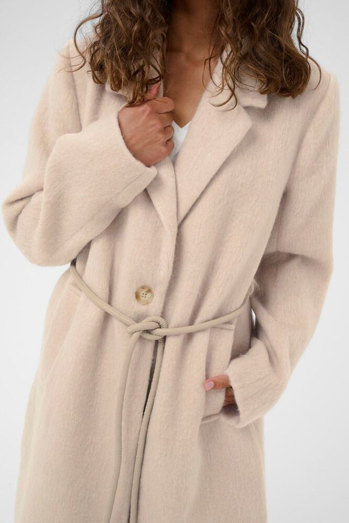 Beige coat worn by a person on a white background