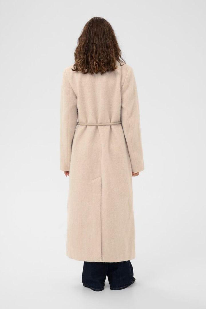 Person wearing a long beige coat on a white background