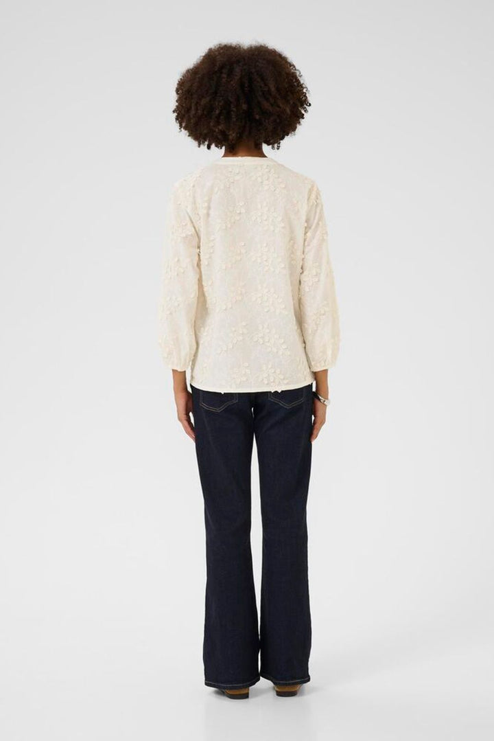 Person wearing a cream sweater and dark pants on a white background