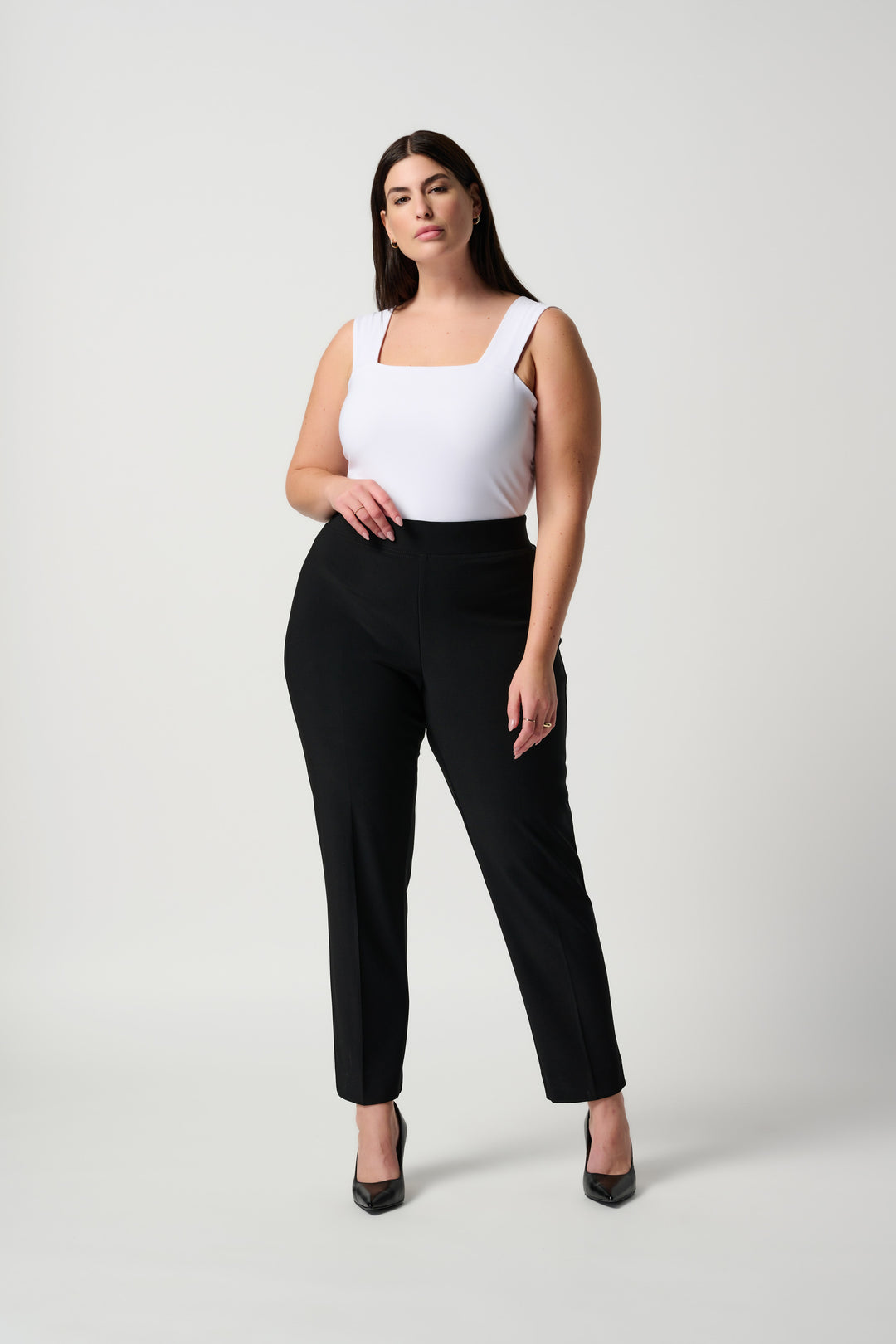 Woman wearing a white top and black pants on a white background